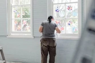 A woman is painting a window in a room.