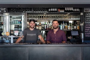 Two men standing in front of a bar.