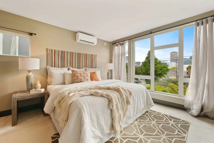 A bedroom with a large window overlooking a city.