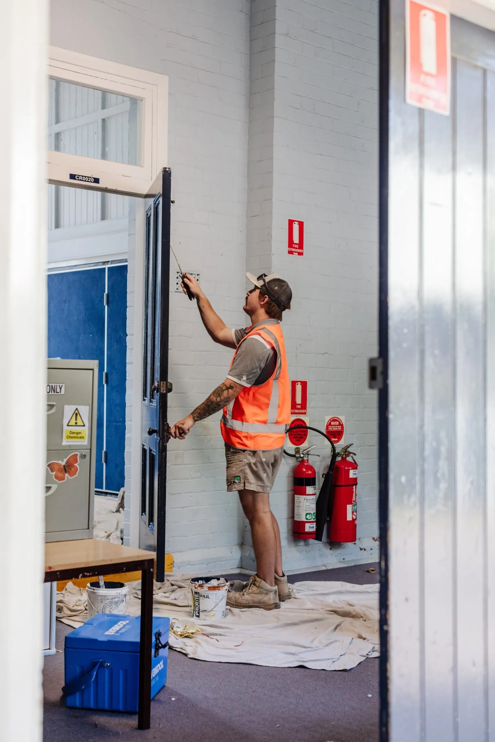 A man is painting a door in a school building.