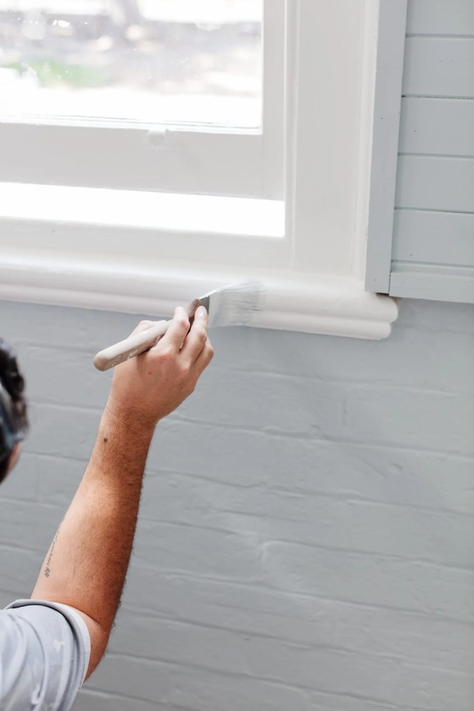 A man revamps the trim of a window.