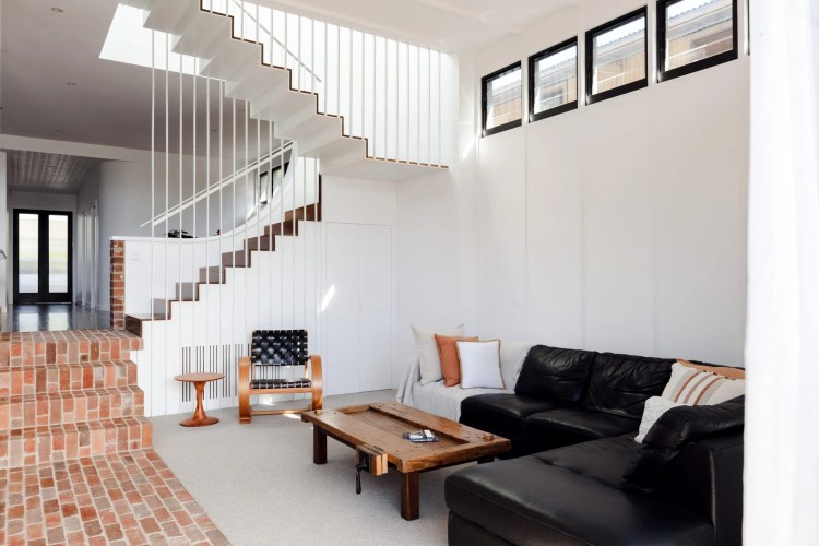 A Denison Street living room adorned with black furniture and a staircase.